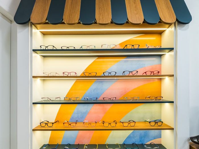 Vitrine de óculos de sol com toldo de madeira e mural colorido ao fundo